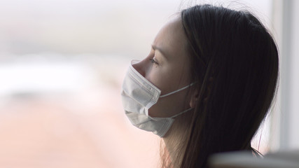 Fearful isolated teen in corona quarantine looking out of window to the street