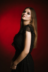 Fototapeta premium Fashion studio portrait of young beautiful woman on black and red background