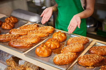 Employees selling fresh pastry and baguettes in local bakery close-up