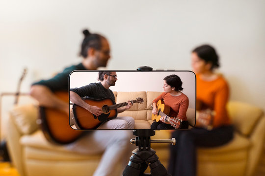 Guitar lessons tutorial with smart phone. Indoor screen shot of musical course. Technology and leisure. Professor teaching how to play an instrument. Video screen recording music online class at home.