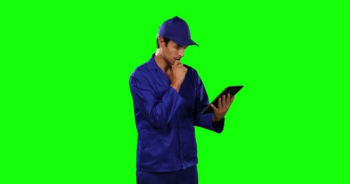 Front view of mechanic using digital tablet with green screen