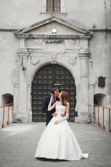 Beautiful bride and groom embracing and kissing on their wedding day outdoors