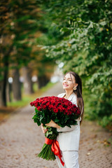 Fototapeta premium Smiling girl with bouquet of red roses
