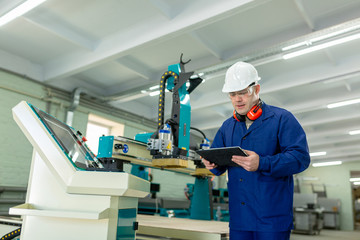 Worker in the Hard Hat Modern Factory CNC machine operator  . Successful, Handsome Man in Modern Industrial Environment.Emotions, Copy Space
