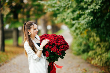 Valentine's Day 101 Birthday Gift For You. Beautiful woman with stylish makeup. Girl holding a gorgeous big bouquet of roses. Perfect sensual lips. Fashion Makeup. Woman in earrings