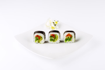 Three sushi on a white square plate on a light background. 