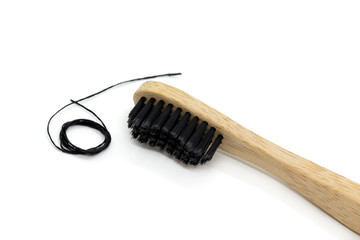Close-up of black dental floss and bamboo toothbrush