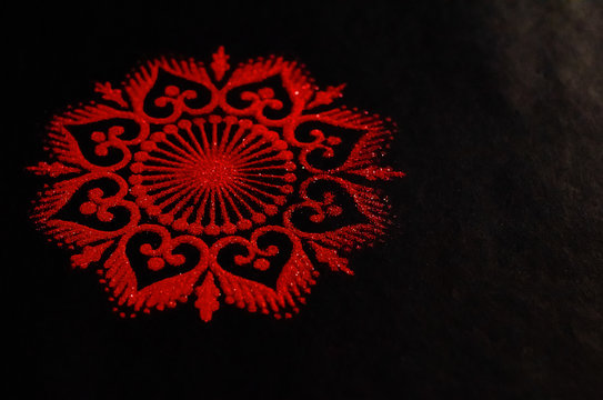Closeup of a red rangoli art on a black background. diwali concept