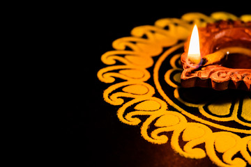 close up shot of one beautiful terracotta lamp with rangoli on black background. diwali concept