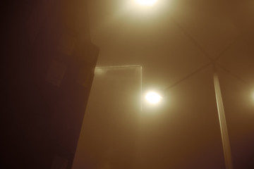 Fototapeta na wymiar Skyscraper house in the fog at night. luminous peak. with a lantern in brown dark colors