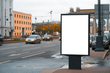 vertical billboard in the city near the road and passing by blurry cars. the size of a person.