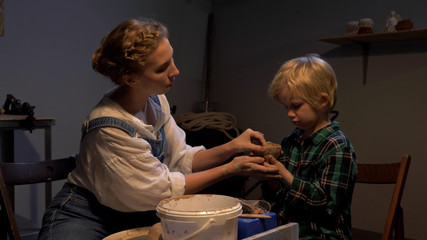 Slow motion, woman helps boy to sculpt in the workshop