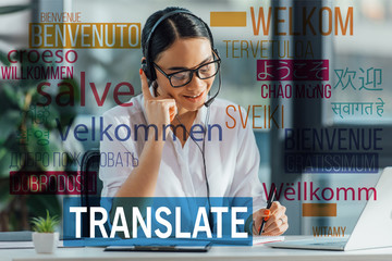 smiling asian translator working online with headset and laptop in office, welcome translation...