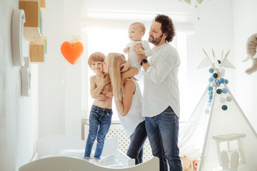 Four family member playing together with two cute boys in a sunny bright room. Enjoying sunny days at home during quarantine. Perfect parenting relationship. Stay home together. Family time