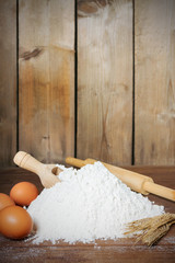 flour, spoon, eggs  and roller on wooden background