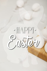 Selective focus of eggs on wooden egg tray and feathers on white background with happy Easter illustration