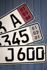 Nummernschilder für PKW Fahrzeuge an einer Wand