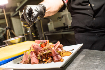 Chev cook makes salad with jerky. Tasty and healthy food for restaurant guests.