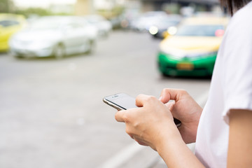 Asian tourist using taxi application on smartphone to make appointment with taxi driver. Woman searching for taxi driver by using smartphone. Modern urban transportation concept with copyspace. © DG PhotoStock