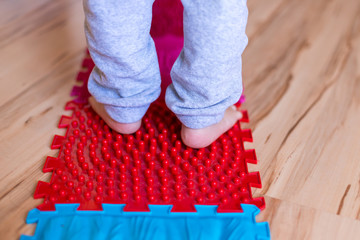 Orthopedic foot mat for child gymnastic. Small children with a flat-bottomed stomach goes barefoot on an orthopedic foot mat for the appointment of an orthopedist.