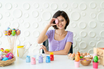 Asian young pretty woman enjoy painting a water colors on fantasy eggs for Easter egg festival. Beautiful colorful fancy Easter egg in bucket. The symbolic of Easter egg festival concept.