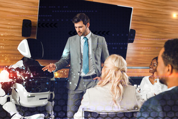 handsome businessman pointing with hand at robot near multicultural colleagues