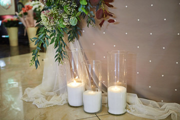Glass vases with white burning  candles stand on the floor