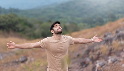 Man enjoying feeling carefree freedom with open arms over nature background in the morning.