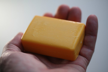 new dry  piece of yellow soap in the hands of a man