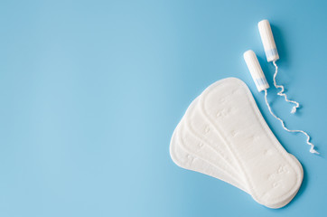 Sanitary pad and tampons on blue background. Concept of feminine hygiene during menstruation. © LunaLu