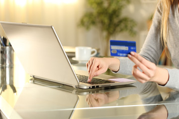 Shopper hands paying with credit card on laptop at home