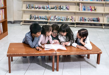 Group of children reading book together,with happy feeling,at library,blurry light around