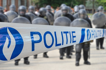 Politie / police tape in front of Belgian riot squad forming a protective barrier with riot shields in Belgium