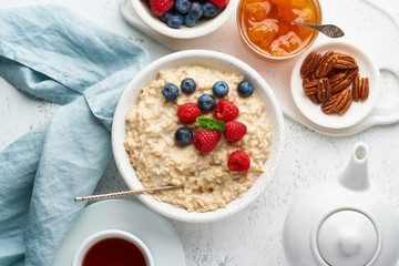Oatmeal porridge with blueberry, raspberries, jam and nuts, top view. Breakfast with berries