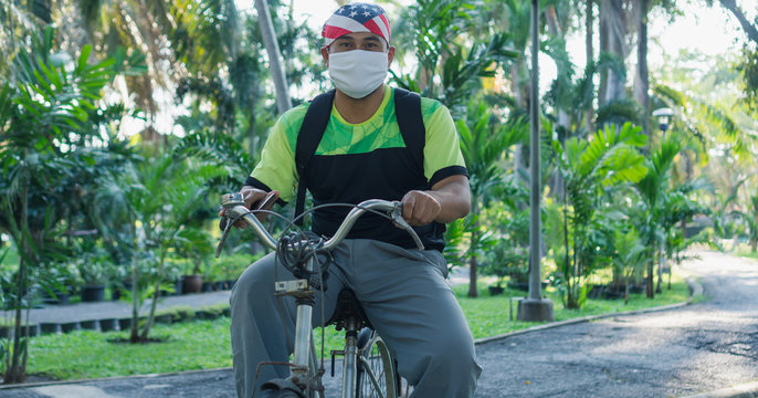 The Male Worker Wears A Mask To Ride A Bicycle.