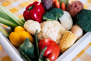 Assortment of fresh raw vegetables, carrots, peppers, cauliflower, broccoli, potatoes, asparagus, corn, tomato - bio agriculture - country yellow tablecloth