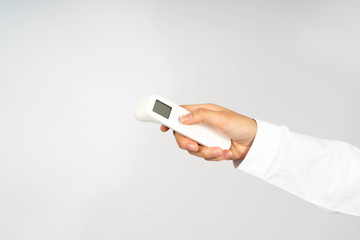 Hand using infrared forehead thermometer (thermometer gun) to check temperature for virus symptom -...