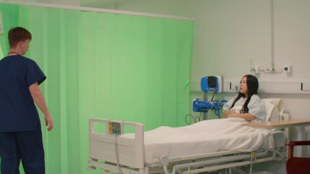 Male Nurse Opens Curtain Talking to Patient