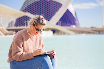 Beautiful woman fashion designer, drawing, sketching and illustrating  with ipad outdoors