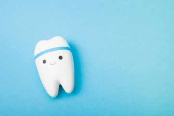 happy tooth on a blue background, copy space, oral care concept, toy tooth model, pediatric dentistry, teach a kid to brush his teeth, first teeth concept
