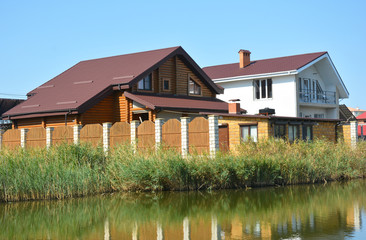 Two-storey brick cottage houses built close to the bank of the river with wooden fence around them.