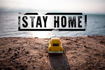 Coronavirus, covid 19 concept. Stay home stamp text and toy car on a background of a sea landscape on a sunny day.