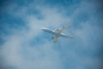 Fototapeta na wymiar Flying plane in the blue, cloudy sky.