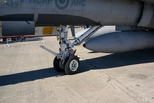 Military Aircraft Of Canadian Air Force -  Jet Plane And Airplane Is Parking On Ground On The Airport. Detail Of Undercarriage And Landing Gear.