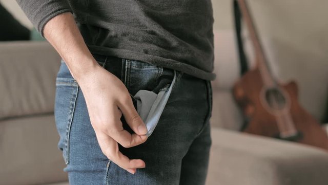 Man showing his empty pockets, turning his pockets inside out. Guitar in the background. Profile of sad musician turning out empty pockets. Money concept.