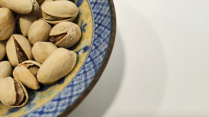 Pistachio nuts heap in the bowl with white background . dried fruit