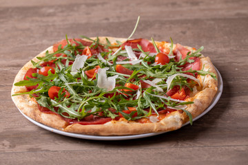 close up of delicious italian fresh pizza with ham, arugula, tomato and parmesan