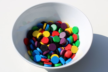 Bunte Spielsteine aus Holz in weißer Schüssel