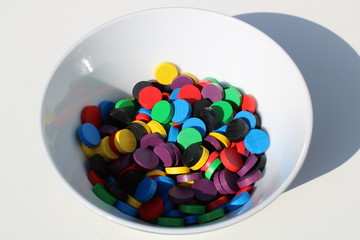 Bunte Spielsteine aus Holz in weißer Schüssel