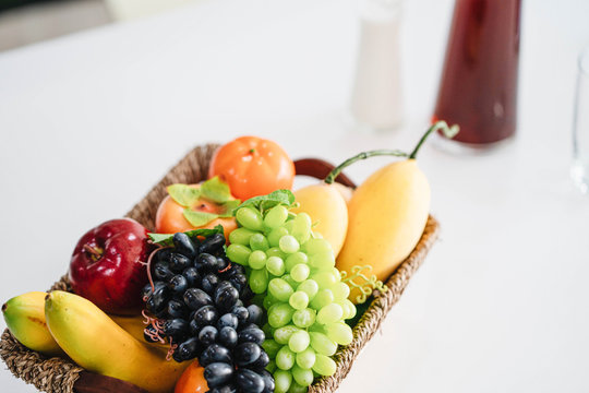 basket with fresh fruit and juice on white modern office table